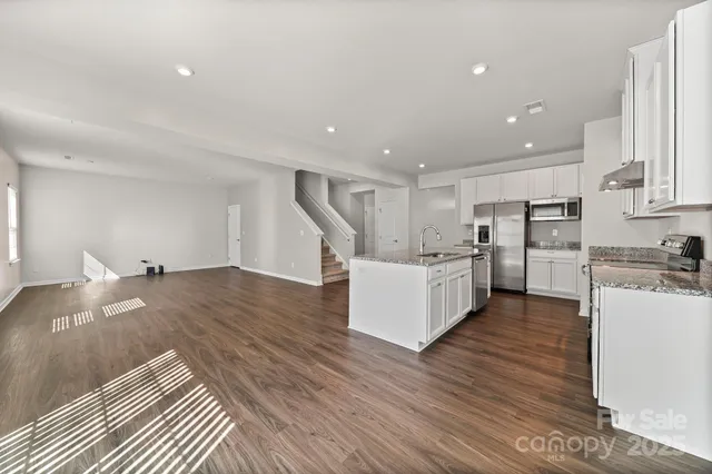 a large white kitchen with wooden floors and stainless steel appliances