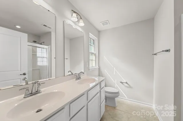 a bathroom with a double vanity sink toilet and a mirror