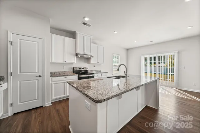 a kitchen with stainless steel appliances granite countertop a sink stove and cabinets