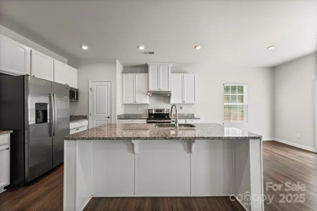 a kitchen with stainless steel appliances granite countertop a refrigerator a sink a stove a microwave and wooden cabinets