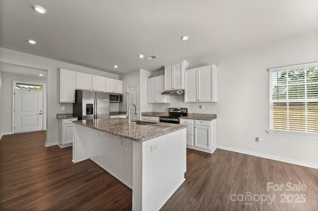 a kitchen with stainless steel appliances granite countertop a sink cabinets and wooden floor