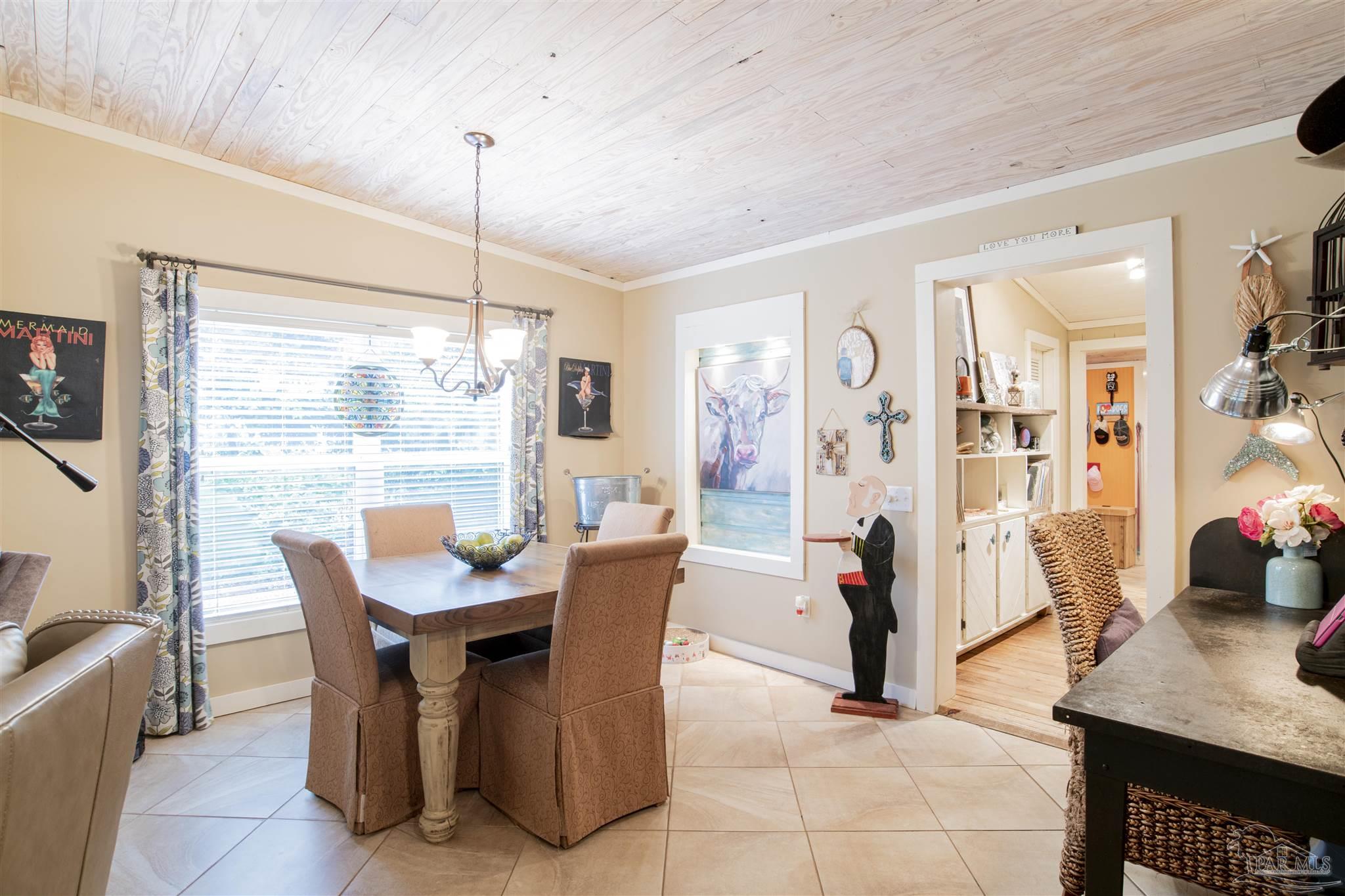 5661 Galvez Road Pensacola, FL 32507 - Photo 46 of 60 a dining room with furniture a window and a chandelier
