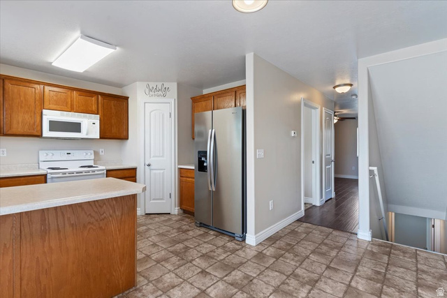 2350 South Highway 89, Unit 4 Perry, UT 84302 - Photo 13 of 30 Kitchen featuring white appliances, light countertops, stone finish floors, and wood finish cabinets