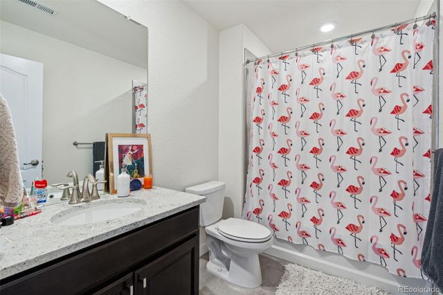 a bathroom with a granite countertop sink a toilet and a shower curtain
