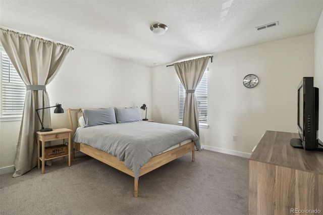 a bedroom with a bed flat screen tv and a large window