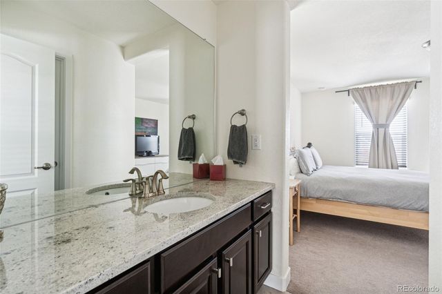 a en suite bathroom with a granite countertop sink and a mirror