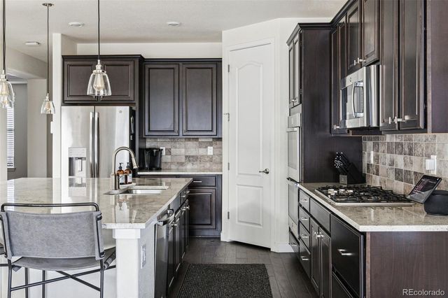 a kitchen with stainless steel appliances granite countertop a stove a sink dishwasher and a refrigerator with wooden cabinets