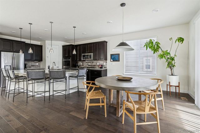 a kitchen with kitchen island stainless steel appliances a dining table chairs sink and cabinets