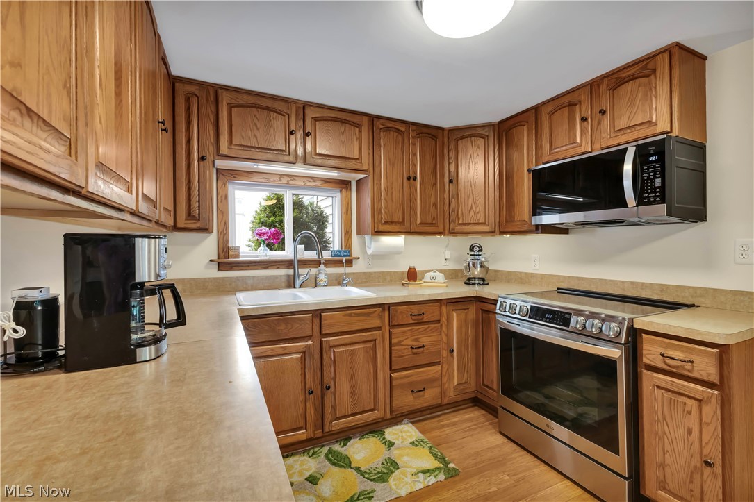8704 Columbia Road Olmsted Falls, OH 44138 - Photo 4 of 34 Kitchen featuring wood cabinetry, light-toned countertops, a stainless steel electric range, and an over-the-range microwave