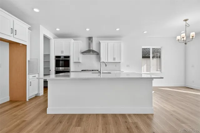 a large kitchen with stainless steel appliances a large counter top a stove and a refrigerator