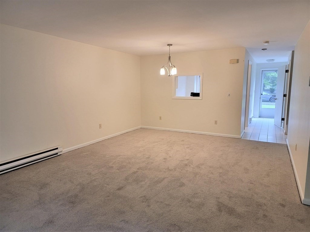 174 Lowell Road, Unit 24 Mashpee, MA 02649 - Photo 8 of 16 an empty room with chandelier fan and windows