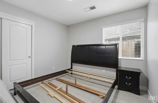 a living room with a flat screen tv on dresser and a window