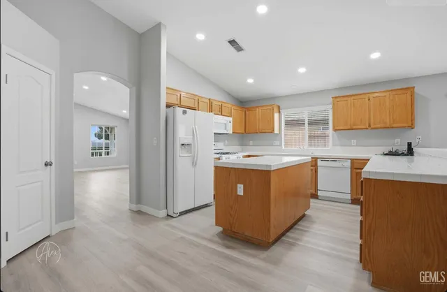 a kitchen with stainless steel appliances granite countertop a refrigerator a sink dishwasher and a stove with wooden floor