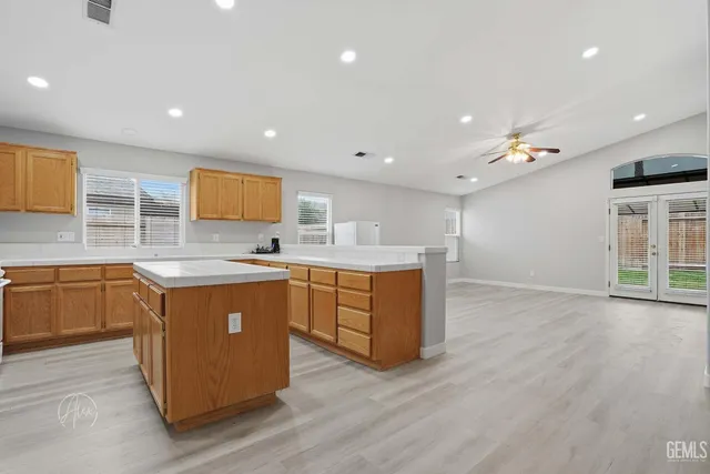 a large kitchen with stainless steel appliances granite countertop a large counter top a stove a sink a refrigerator and a microwave