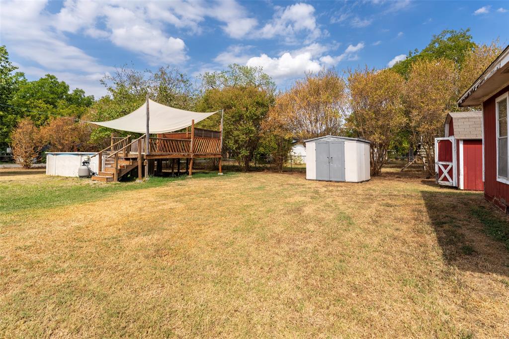 1101 Kennedale Sublett Road Kennedale, TX 76060 - Photo 29 of 35 Expansive backyard featuring a wood deck, shade sail, and two storage sheds