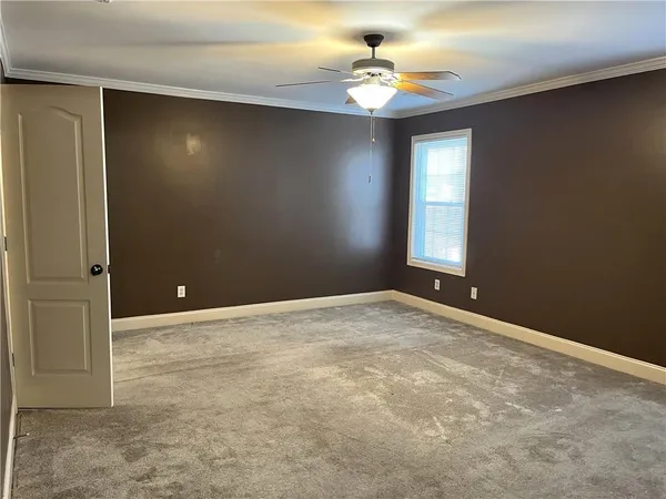 an empty room with windows and chandelier fan