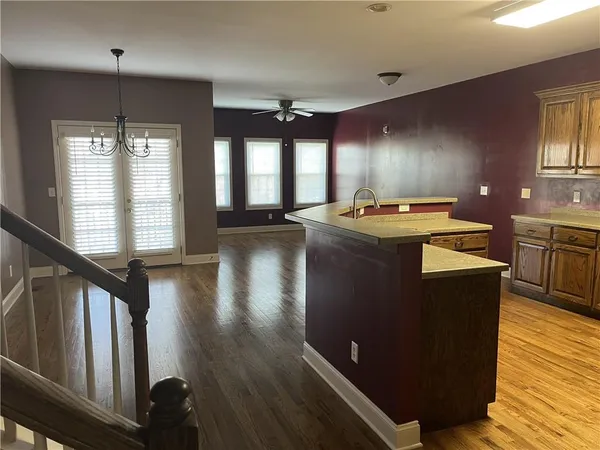 a kitchen with kitchen island granite countertop a stove a sink a refrigerator wooden floor and cabinets