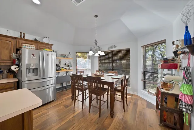 a kitchen with stainless steel appliances a dining table chairs and wooden floor