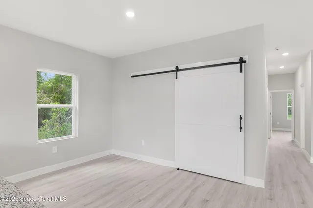 an empty room with wooden floor a ceiling fan and windows