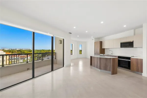 a view of kitchen with stainless steel appliances kitchen island granite countertop a stove and a large window