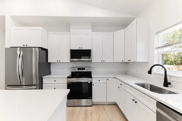 a kitchen with stainless steel appliances granite countertop a refrigerator sink and white cabinets