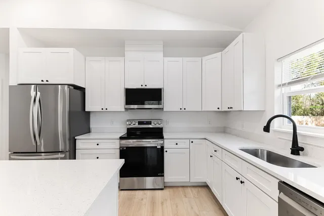 a kitchen with stainless steel appliances granite countertop a refrigerator sink and white cabinets