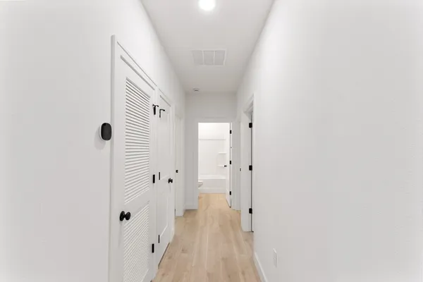 a view of a hallway with wooden floor and a bathroom