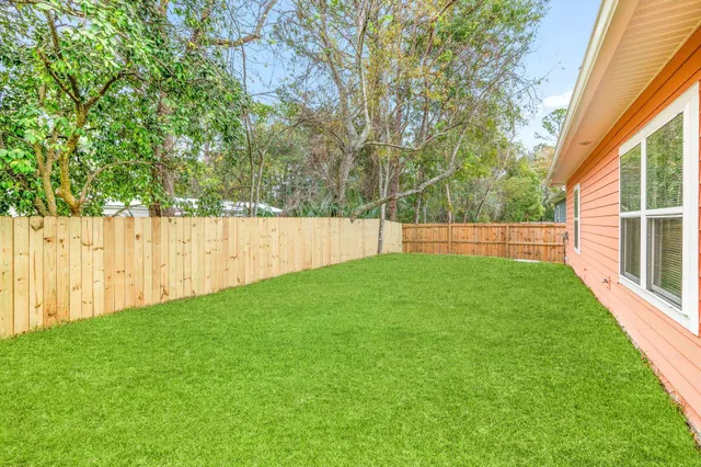 a view of yard with grass and trees in the background