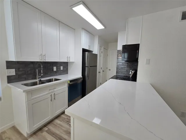 a kitchen with a refrigerator sink and cabinets