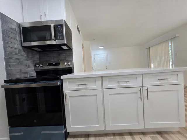 a kitchen with white cabinets and black appliances