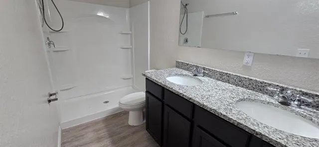a bathroom with a granite countertop sink a toilet and shower