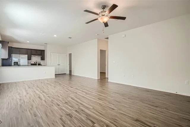 an empty room with wooden floor a ceiling fan and a ceiling fan