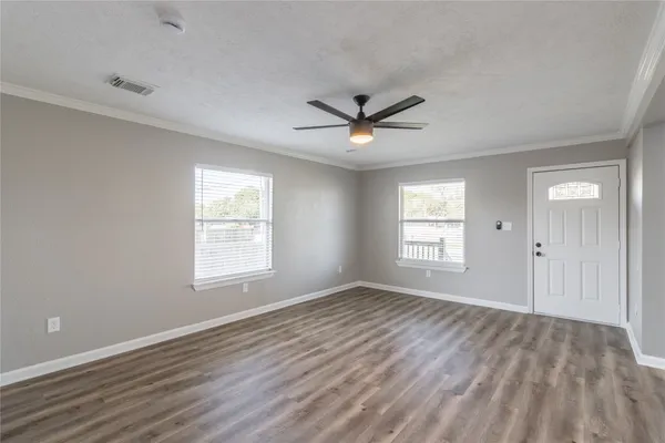 a view of a big room with wooden floor and windows
