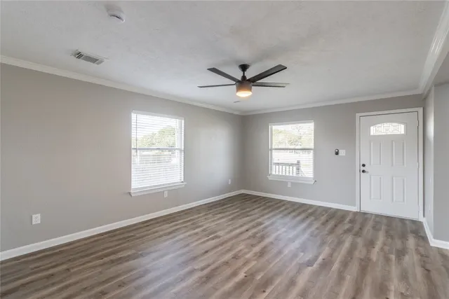 a view of a big room with wooden floor and windows