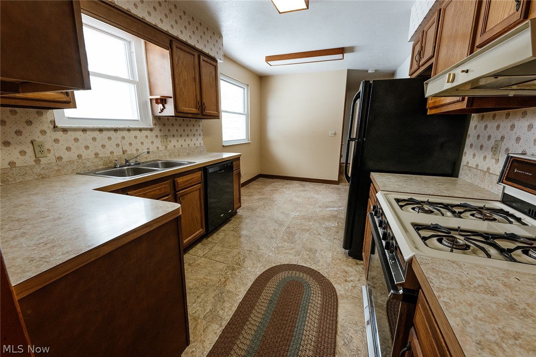 19545 Alexander Road Bedford, OH 44146 - Photo 11 of 29 Kitchen featuring black dishwasher, light tile flooring, sink, and white gas range oven