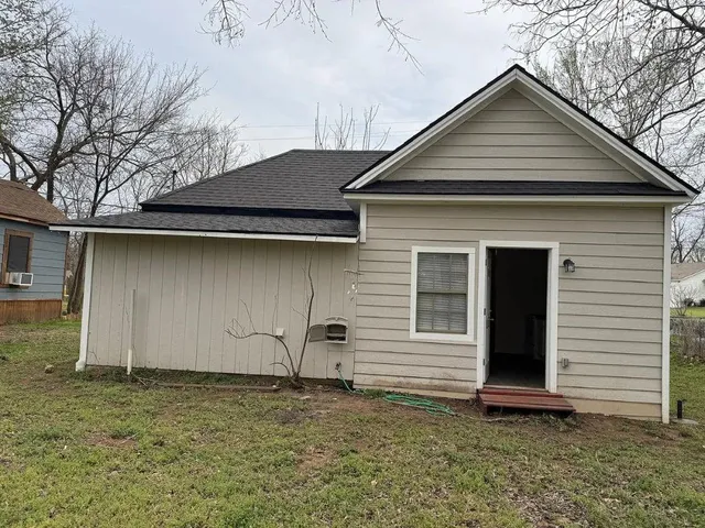 a small white house with a yard and garage