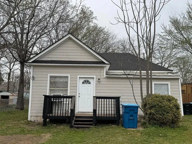 a front view of house with yard and trees in the background