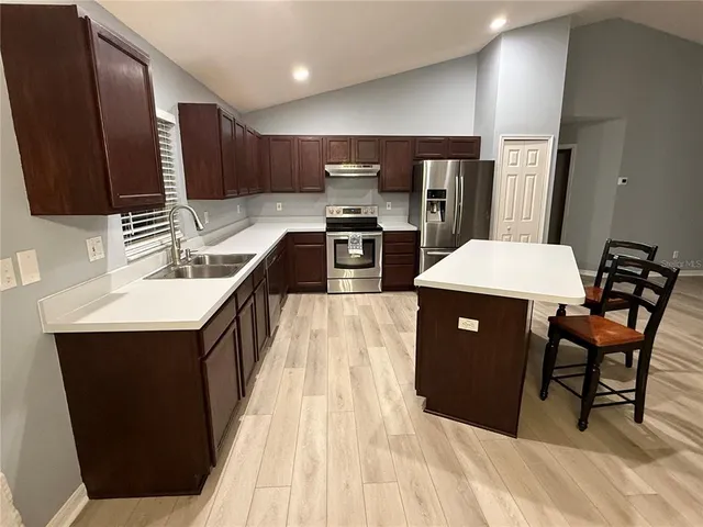 a kitchen with stainless steel appliances kitchen island granite countertop a sink a stove and a refrigerator