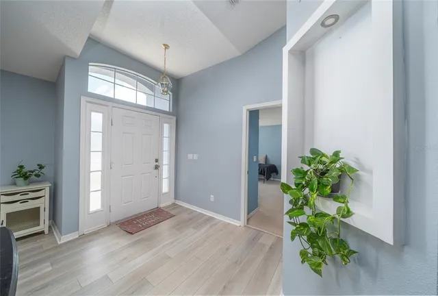 an empty room with wooden floor and a chandelier
