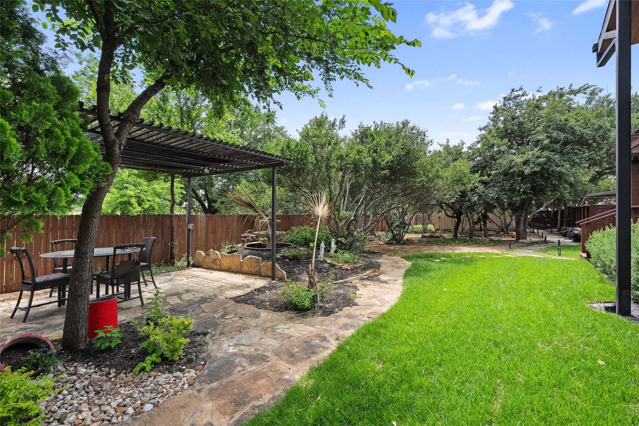 301 Oak Ridge Road Georgetown, TX 78628 - Photo 24 of 34 Spacious backyard with a stone patio, a metal pergola, a lush lawn, mature trees, and a wood privacy fence