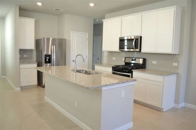a kitchen with stainless steel appliances granite countertop a sink a stove a refrigerator a washer and dryer