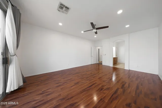 a view of empty room with wooden floor and fan
