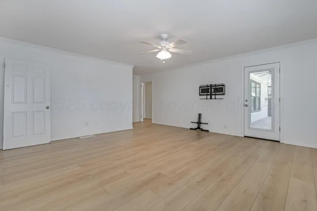 a view of empty room with wooden floor and fan