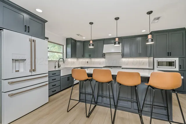 a kitchen with stainless steel appliances granite countertop a table chairs stove and cabinets