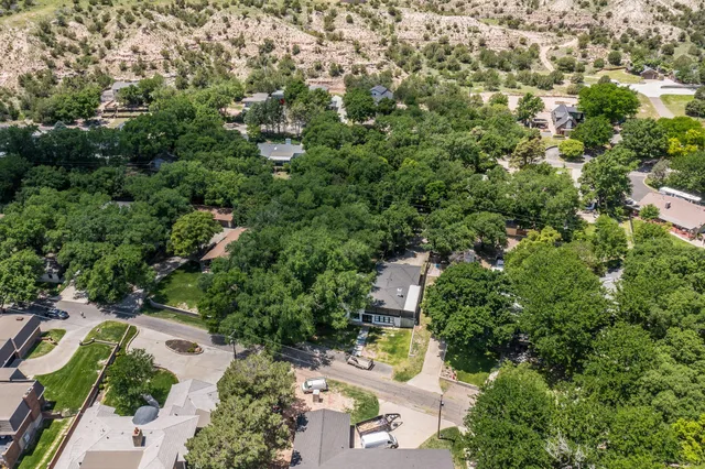 an aerial view of residential house with outdoor space and trees all around