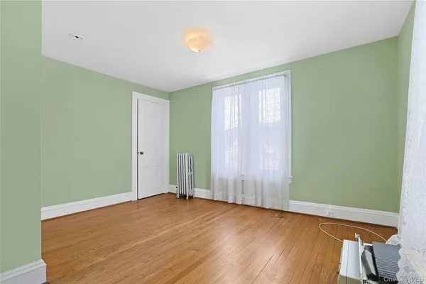a view of an empty room with window and wooden floor