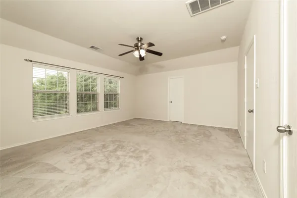 an empty room with windows and fan