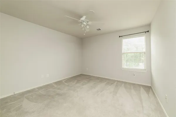 an empty room with chandelier fan and windows