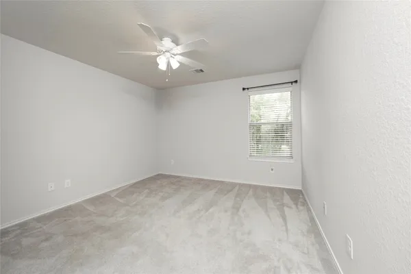 an empty room with windows and chandelier fan