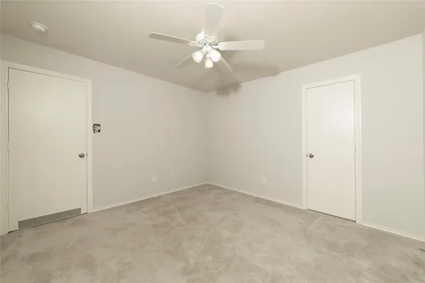 an empty room with chandelier fan and windows